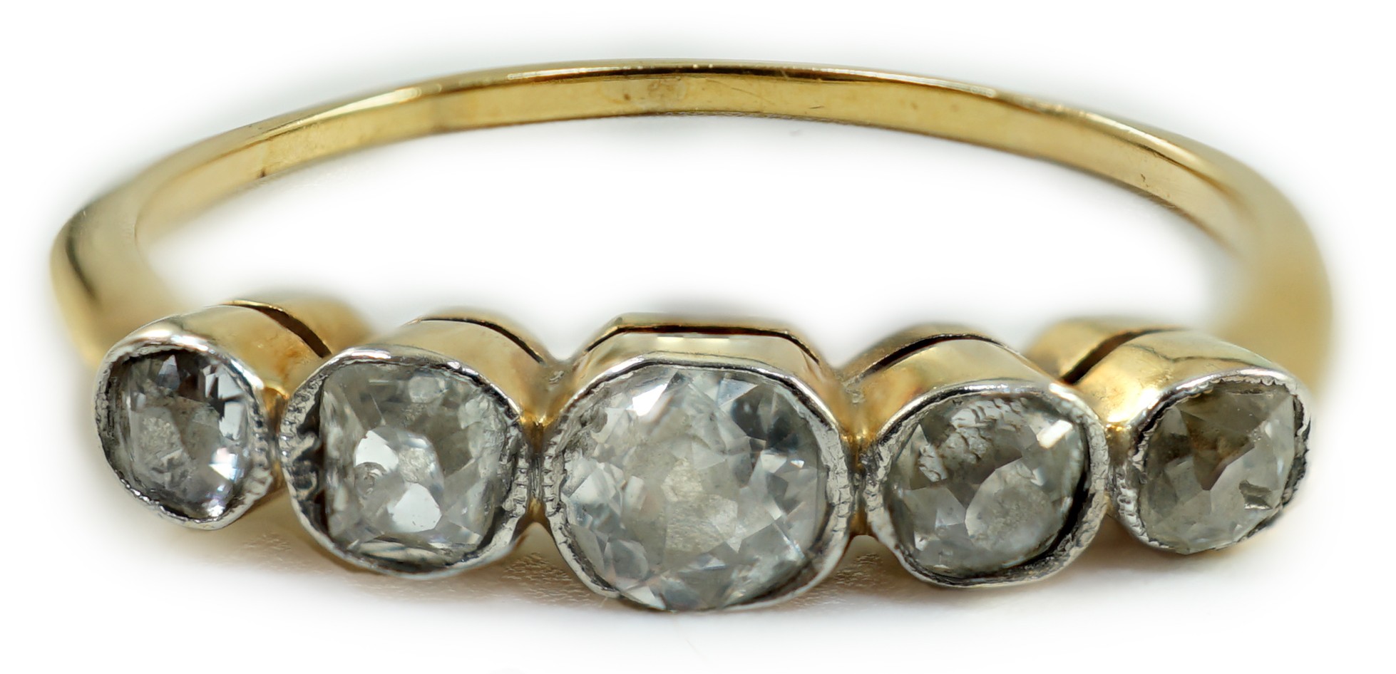 A yellow metal and graduated collet set five stone diamond half hoop ring, size V, gross weight 2.6 grams.
